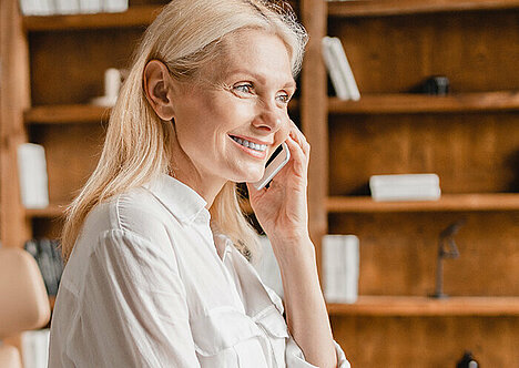 Jobsuche: Ältere Frau telefoniert im Büro und lächelt