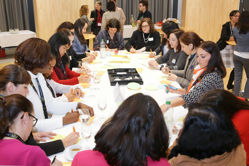 Teilnehmerinnen am Mentorinnen-Programm für Migrantinnen sitzen gemeinsam an einem ovalen Tisch und schreiben auf Notizzettel.