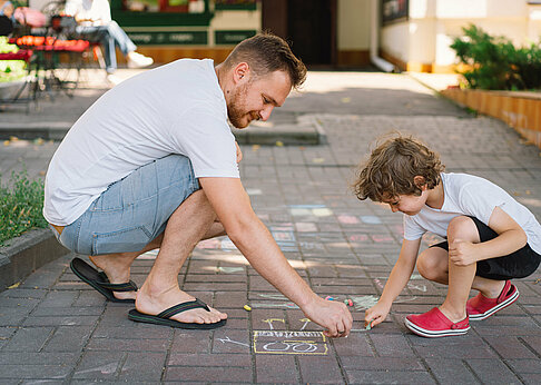 Väterstudie: Papa malt mit Kind auf der Straße