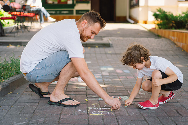 Väterstudie: Papa malt mit Kind auf der Straße