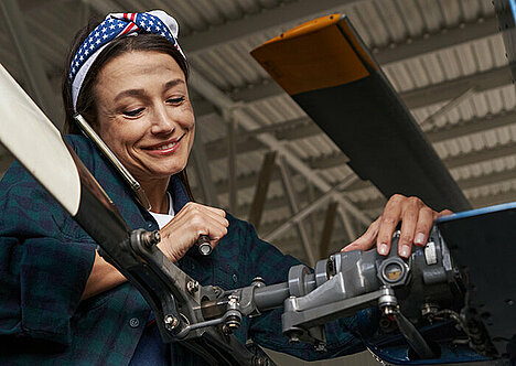 Berufliche Orientierung: Mechanikerin lächelt und repariert Fahrzeug