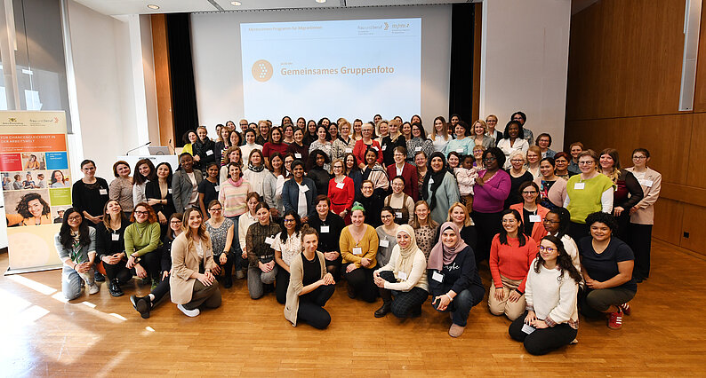 Auftakt des Mentorinnen-Programms: Gruppe von Frauen steht oder sitzt in einem großen Saal